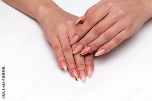 Beige manicure on sharp long nails with black-orange stripes close-up on a white background. Nude manicure.