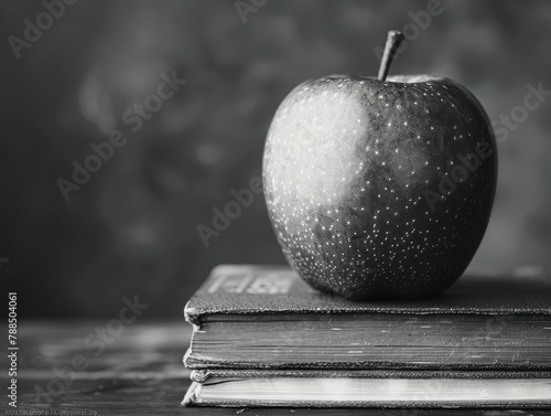 A black and white photo of an apple on a stack of books.