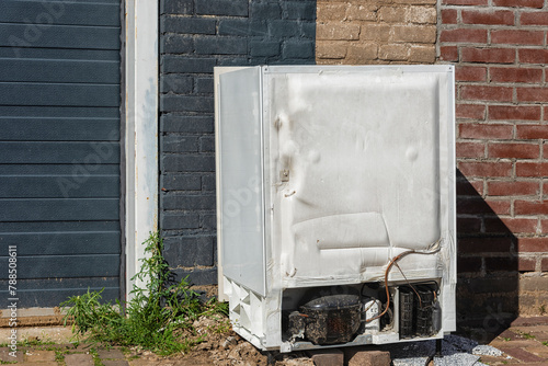white refrigerator stands outside like trash dumped photo
