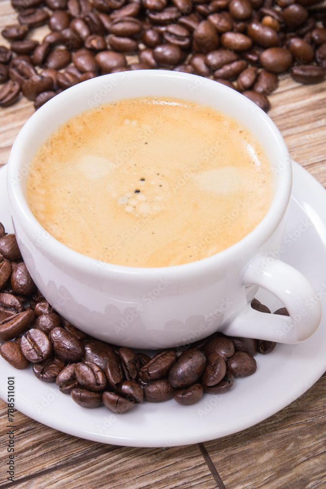 White cup of coffee and roasted fragrant dark coffee grains White cup of coffee and roasted fragrant dark coffee grains