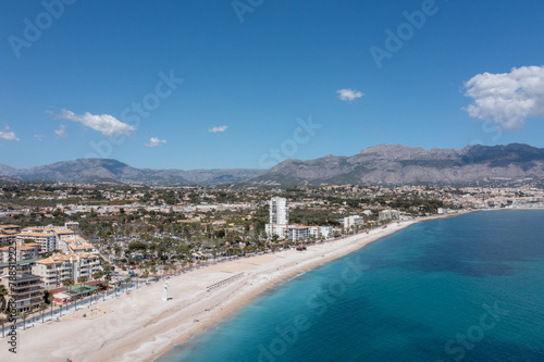 Aerial drone photo of the Spanish town of L'Albir in Spain Alicante showing the beach front on a sunny summers day with the Spanish mountains in the background © Duncan