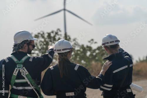 Engineers man and woman inspecting construction of WIND TURBINE FARM. WIND TURBINE with an energy storage system operated by Super Energy Corporation. Workers Meeting to check AROUND THE AREA.