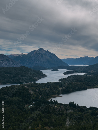 A mountain range with a lake in the valley below. The sky is cloudy and the mountains are covered in snow