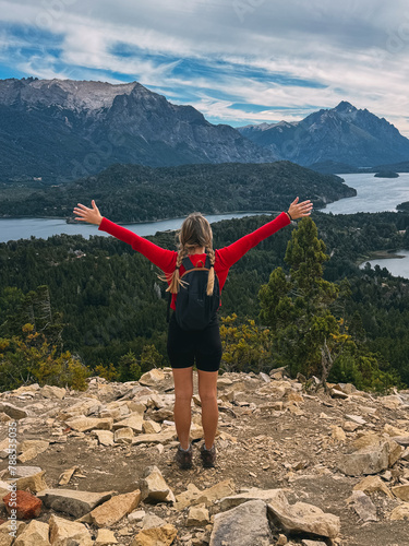 A woman stands on a mountain top, arms outstretched, with a backpack on her back. Concept of freedom and adventure, as the woman is embracing the beauty of nature
