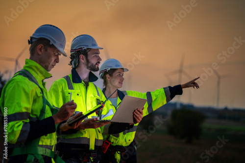 Team Engineers men and woman checking and inspecting on construction with sunset sky. people operation. Wind turbine for electrical of clean energy and environment. Industrial of sustainable.