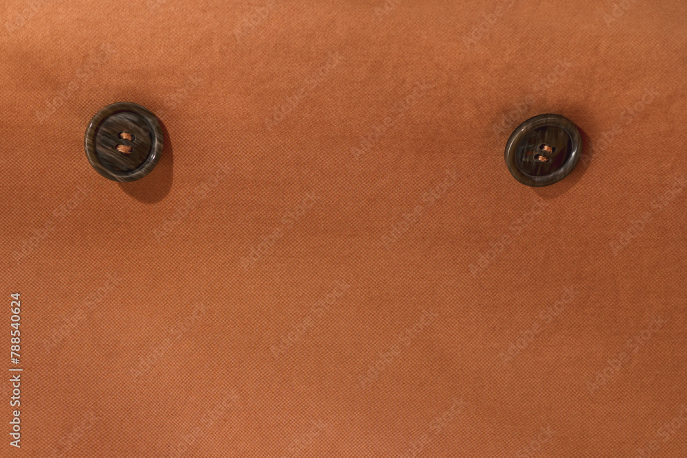 Two buttons on a terracotta cloak. Textile background with buttons. Two buttons on a terracotta cloak. Textile background with buttons.