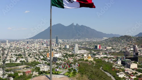 Aerial Ascending Shot Of Tall Flag At Mirador Del Obispado On Hill In City Near Mountains Against Sky - Monterrey, Mexico photo
