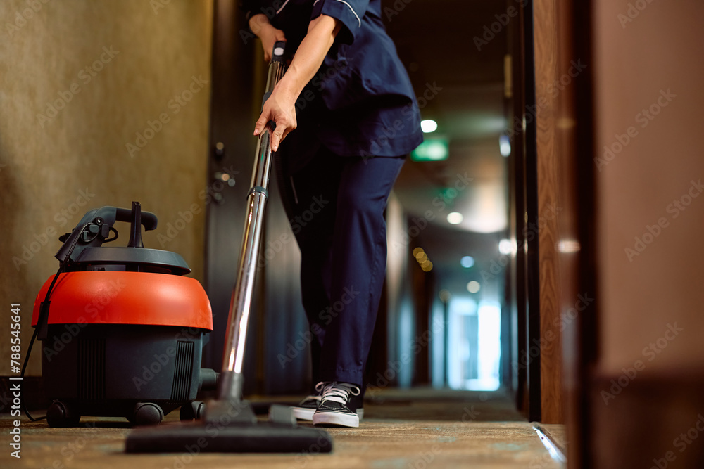 Fototapeta premium Close up of woman vacuuming hallway while working as maid in hotel.