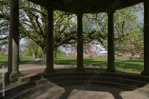 With breathtaking pink cherry blossoms in the distance, the Tewit Well stone spa water well is a beautiful sight, The Stray,Harrogate, England, UK.