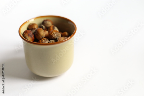 stack of hazelnuts in a cup on white background