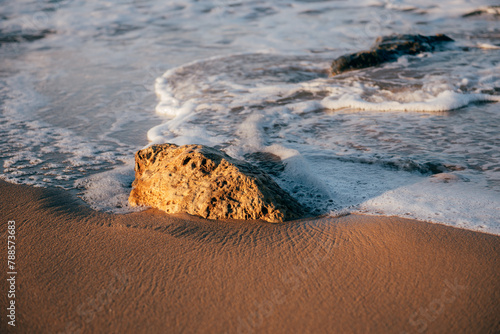 sea, waves, beach, sand and stone at sunset time.