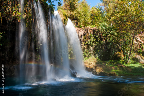 Duden Waterfall cascading into a blue pool with a visible rainbow  surrounded by rich green foliage in Antalya  Turkey.