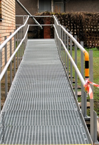 a metal ramp for the disabled and baby carriages at the wall of the building