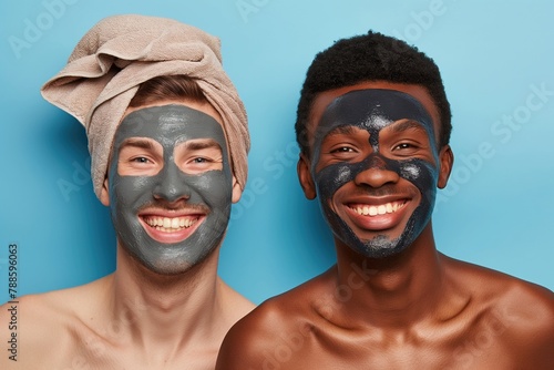 Two diverse joyful friends males with clay masks, on blue background