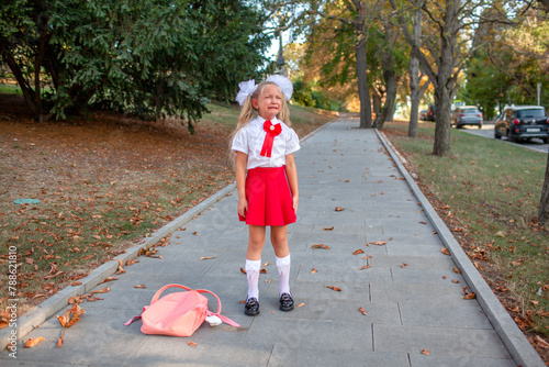 A Girl in uniform with backpack crying on the street