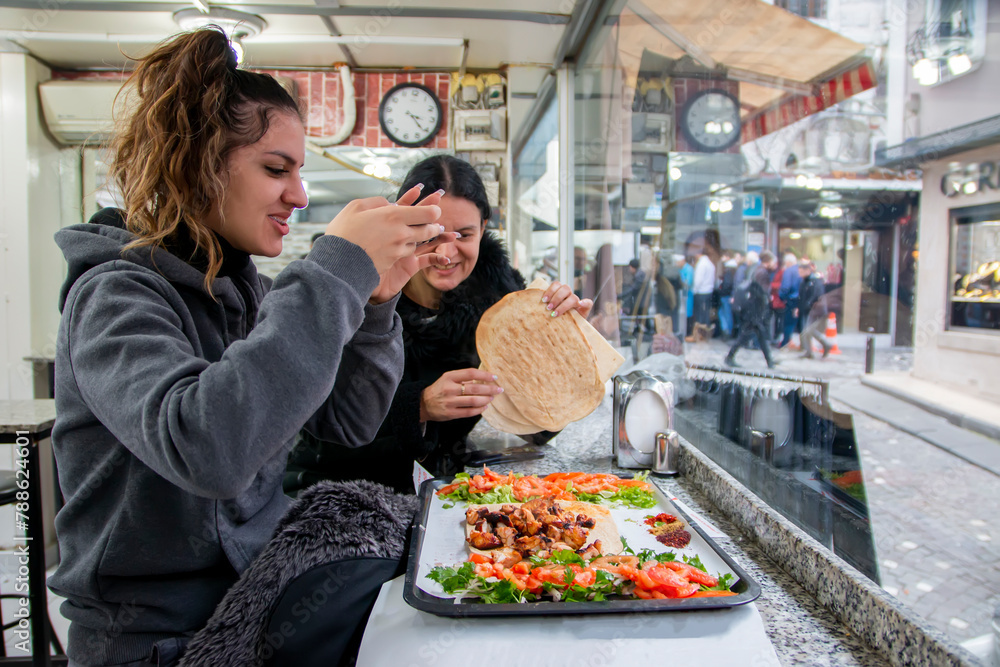 A beautiful young woman and her mom eat and laugh in a restaurant in istanbul, turkey