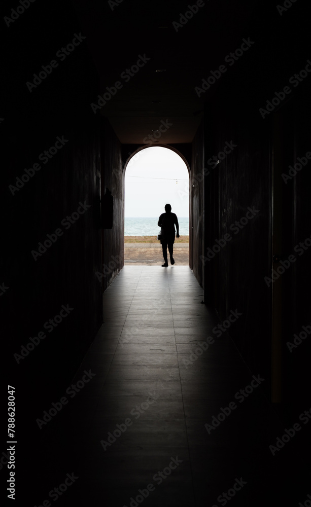 silhouette of a person walking in a tunnel