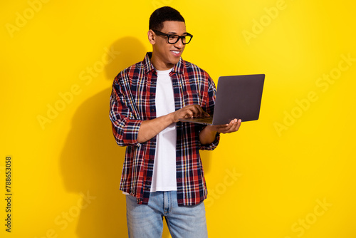 Portrait of nice young man use wireless netbook wear shirt isolated on yellow color background