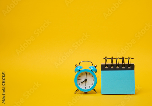 Round alarm clock and blue stickers on a yellow background