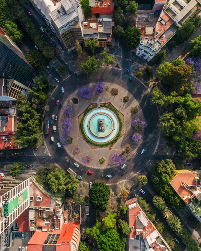 Aerial drone view of Cibeles fountain, a landmark in Colonia Roma in Mexico City with jacaranda trees, Mexico. photo