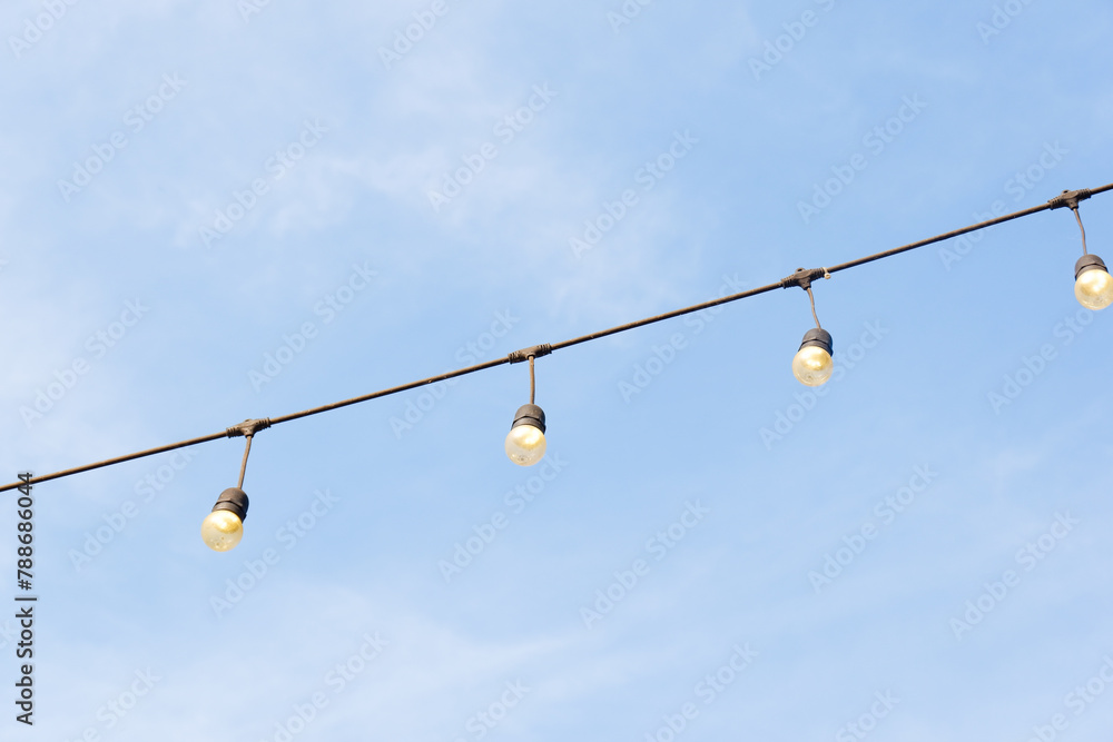 Light bulbs with blue sky,Decorative outdoor string lights hanging on tree in the garden,copy space,garden concept. Light bulbs with blue sky,Decorative outdoor string lights hanging on tree in the garden,copy space,garden concept.