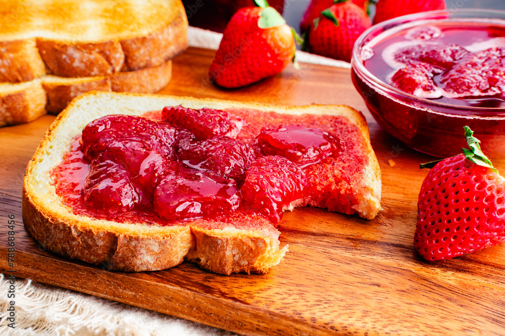 Slice of Toast and Homemade Strawberry Preserves and Missing a Bite: Bitten piece of toasted white bread covered with homemade strawberry preserves Slice of Toast and Homemade Strawberry Preserves and Missing a Bite: Bitten piece of toasted white bread covered with homemade strawberry preserves