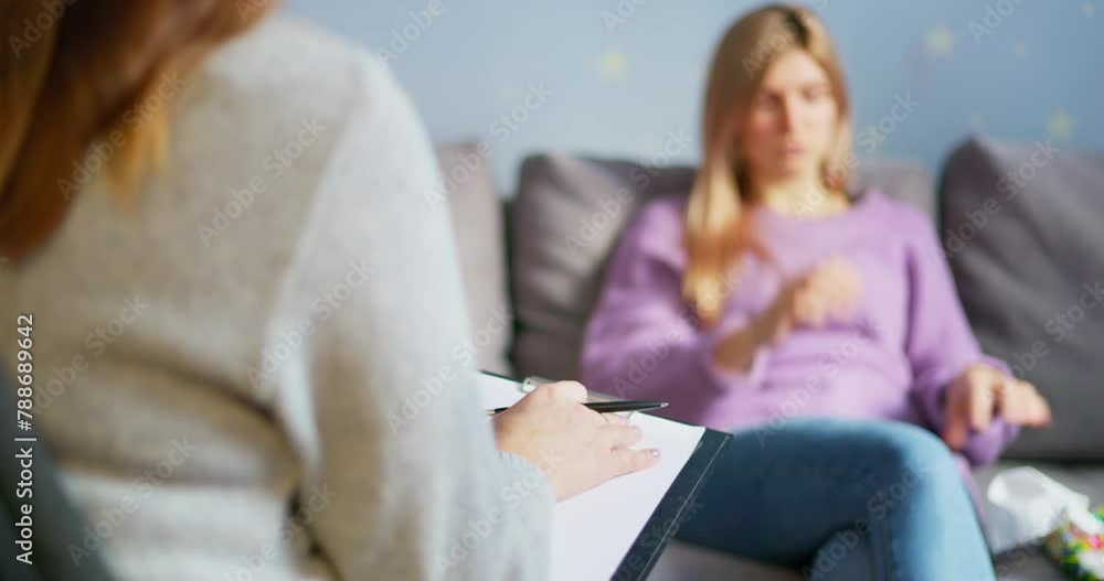 Blurred client in a therapy session with focus on psychologist's notepad Blurred client in a therapy session with focus on psychologist's notepad