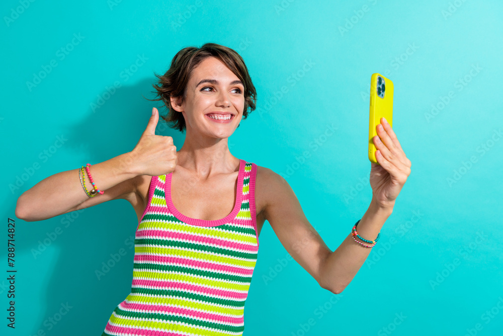 Portrait of charming positive lady hold smart phone take selfie demonstrate thumb up isolated on turquoise color background