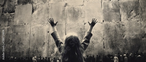 A little girl standing against a wall and raising her both hand. balck and white colour