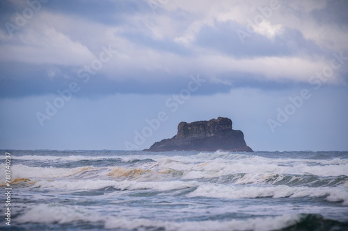 Castle Rock is a large monolith right off the coast of Arch Cape, Oregon. It is named Castle Rock because it resembles a castle turret. Seen here just after sunrise with dramatic cloud cover.