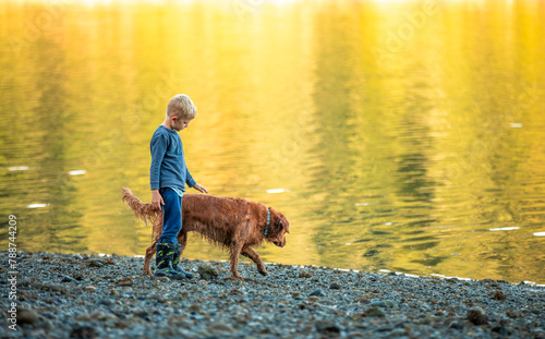 A boy and his pet dog waling together bonding in nature sunset 
