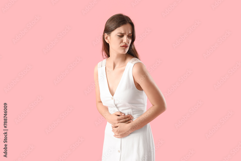 Young woman suffering from stomach ache on pink background Young woman suffering from stomach ache on pink background
