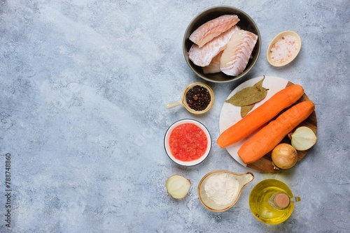 Prepared ingredients for cooking Christmas fish in a sauce with carrots, onions and tomatoes in a Polish style on a light concrete background. Top view