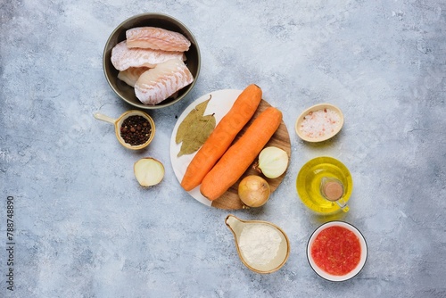 Prepared ingredients for cooking Christmas fish in a sauce with carrots, onions and tomatoes in a Polish style on a light concrete background. Top view