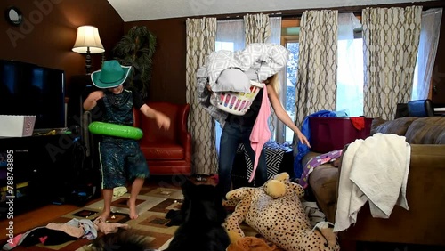 A housewife is stressed and tired trying to clean the house while wild children are running around making a mess for a discipline or parenting concept.