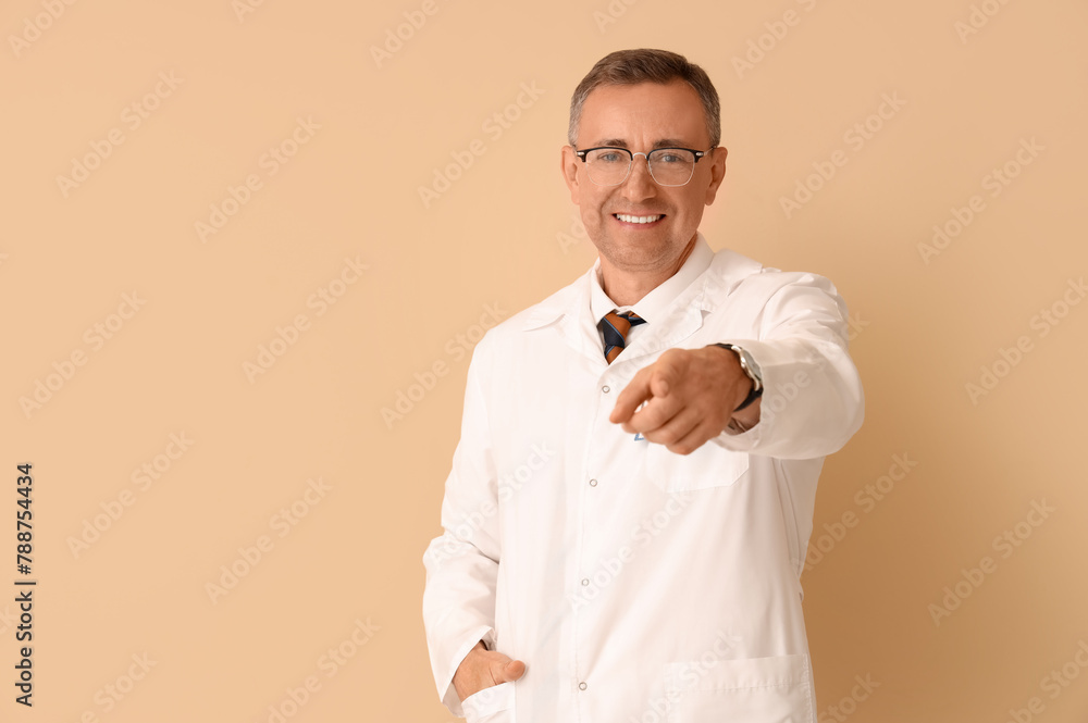 Mature doctor pointing at viewer on beige background Mature doctor pointing at viewer on beige background