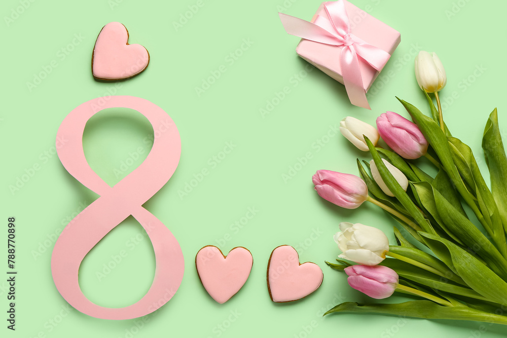 Figure 8 made of paper with tulip flowers, gift box and cookies on green background. International Women's Day celebration
