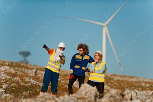 A team of engineers and workers oversees a wind turbine project at a modern wind farm, working together to ensure the efficient generation of renewable energy