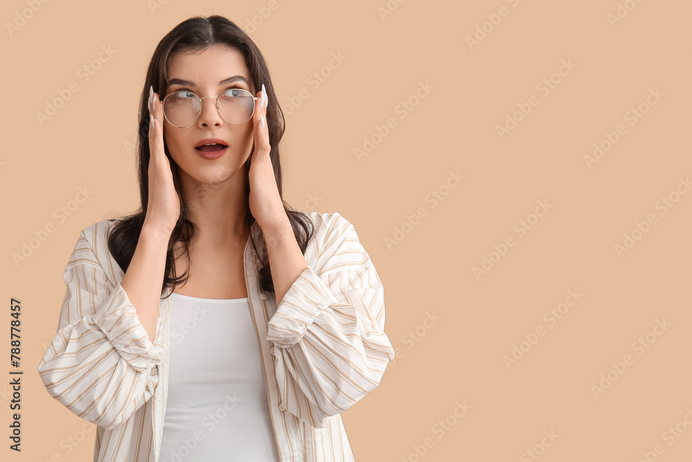 Surprised young woman in eyeglasses on beige background Surprised young woman in eyeglasses on beige background