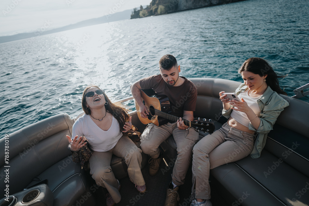 Young adults having fun on a boat, with one playing guitar and another using a smart phone, against a backdrop of sea and sky