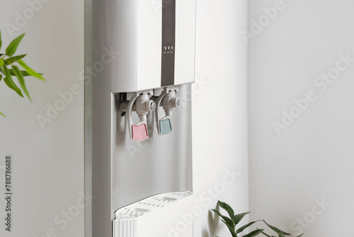 Modern water cooler near white wall