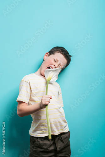 Boy grimacing while holding a large flower photo