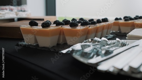 Catering service preparing dessert table with panna cotta and blackberries