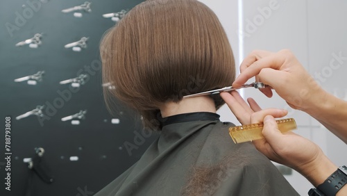 Hairdresser trimming brown hair with scissors at salon