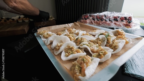Caterer arranging shrimp appetizers on rice crackers for an event
