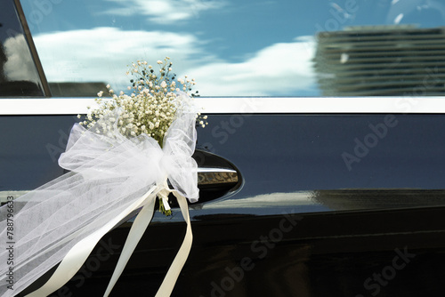 Wedding bouquet of fresh flowers on the doorknob of a wedding car