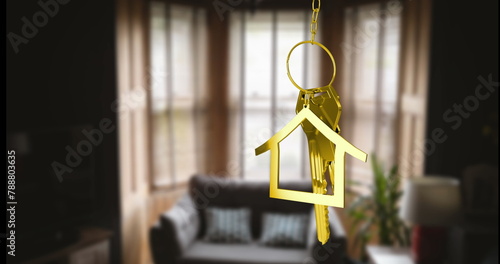 Keychain shaped like a golden house in focus, living room with sofa and plants blurred