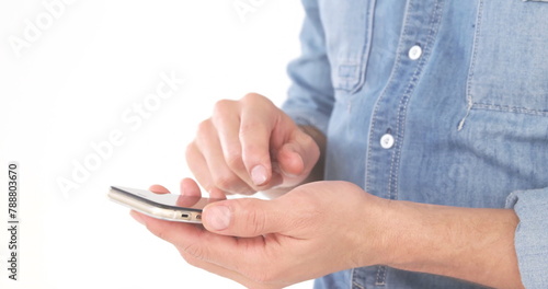 A person wearing blue shirt holding and typing on a smartphone