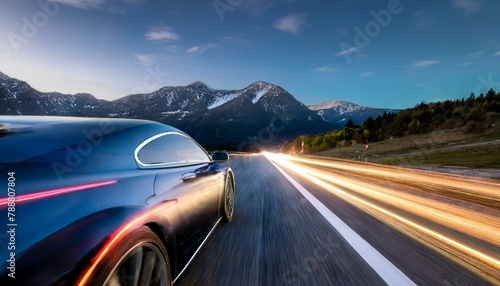 A fast car speeding down the road with light trails on right going into the mountains