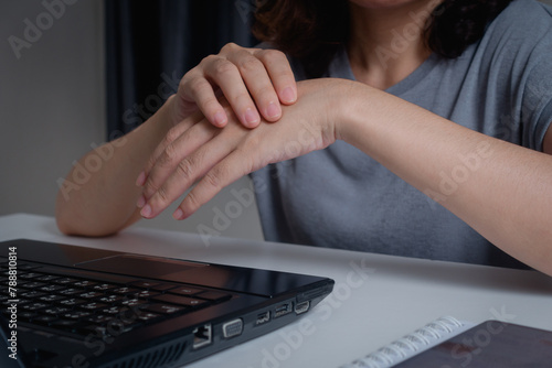Closeup of woman holding her wrist pain from using a laptop computer long time. Carpal tunnel syndrome or wrist joint inflammation, arthritis, neurological disease, Numbness hand, office syndrome.
